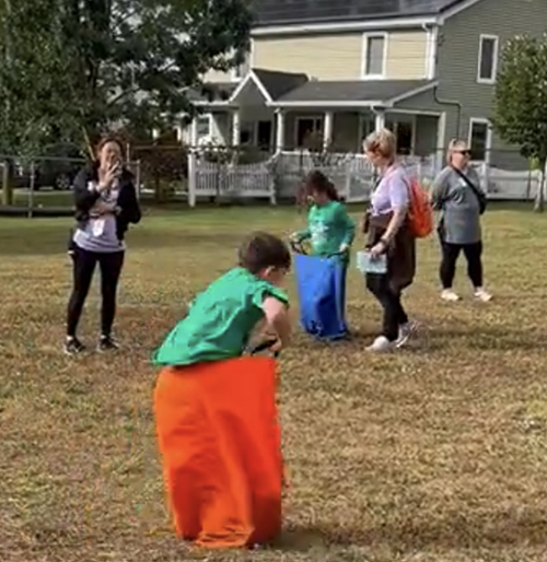 Students jumping in potato sacks with teachers cheering them on