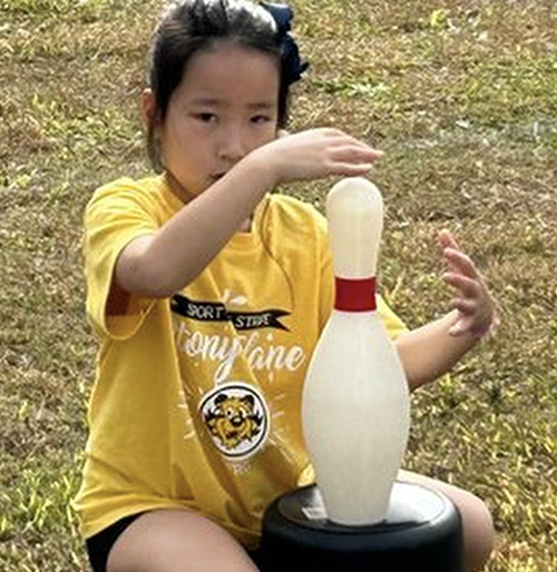 Student focused on balancing bowling ball pin