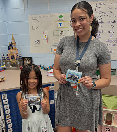 Student next to teacher holding their badges