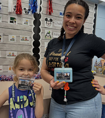 Student and teacher holding their badges up